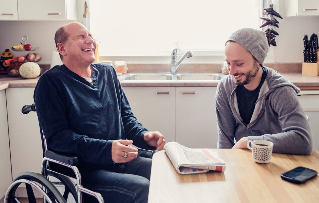 Disabled man laughing with support worker in kitchen